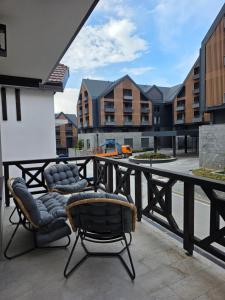 a balcony with two chairs and a building at Arija Luxury Suite in Kolašin