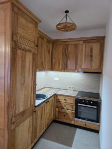 a kitchen with wooden cabinets and a sink and a chandelier at Arija Luxury Suite in Kolašin