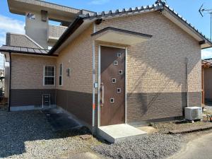 a brick house with a brown door on it at ラフォーレハウス in Hitoyoshi