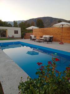 a swimming pool with tables and umbrellas in a backyard at Cabañas Lodge el Mauco in Curacaví