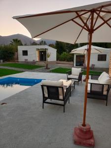 a patio with an umbrella next to a pool at Cabañas Lodge el Mauco in Curacaví