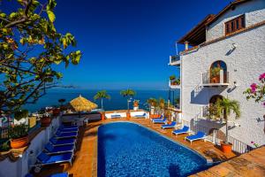 a view of a hotel with a pool and chairs at Charming condo featuring ocean views, pool & private terrace in Puerto Vallarta