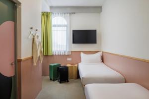 a room with two beds and a flat screen tv at mu petite in Ipoh