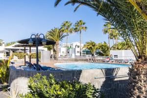 a pool at a resort with palm trees at Casa Bodega Coco in Puerto del Carmen