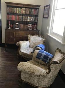 a living room with two chairs and a book shelf at The Historic Railway Barracks in Goulburn
