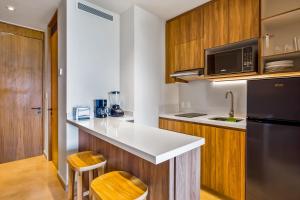 a kitchen with a black refrigerator and wooden cabinets at Oceanfront Gem with Bay View Terrace & Direct Sea Access in Cruz de Huanacaxtle