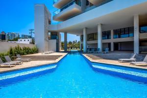 a swimming pool in front of a building with chairs at Oceanfront Gem with Bay View Terrace & Direct Sea Access in Cruz de Huanacaxtle