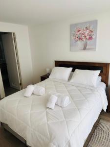a bedroom with a large white bed with towels on it at Departamento Temuco Centro in Temuco