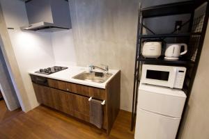a small kitchen with a sink and a microwave at Fukugi Beach Villa Okinawa in Nakijin