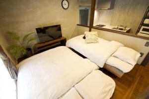 two beds in a small room with a tv at Fukugi Beach Villa Okinawa in Nakijin +82 photos
