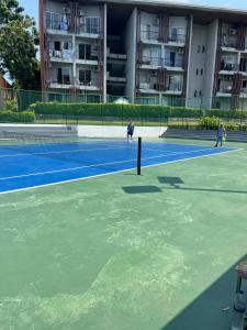 three people playing tennis on a tennis court at Cozy 1-Bedroom Apartment Near Fisherman's Village in Nathon Bay