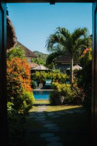 a house with a swimming pool and palm trees at Co Day Uluwatu Boutique Stays in Uluwatu