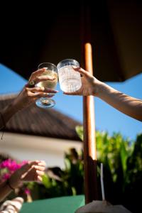 two people holding up glasses of beer at Co Day Uluwatu Boutique Stays in Uluwatu