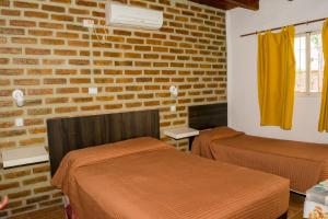 a room with two beds and a brick wall at Cabañas de Campo in Villa Unión