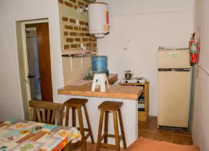 a kitchen with a counter with stools and a refrigerator at Cabañas de Campo in Villa Unión +16 photos