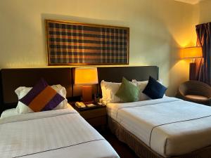 a hotel room with two beds and a chair at Tunamaya Beach & Spa Resort Tioman Island in Tioman Island