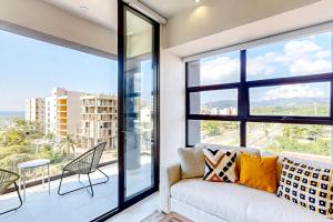 a living room with a couch and a large window at Ocean-view condo with infinity pool, rooftop lounge, & private balcony in Bucerías