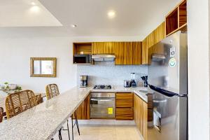 a kitchen with wooden cabinets and a stainless steel refrigerator at Ocean-view condo with infinity pool, rooftop lounge, & private balcony in Bucerías +20 photos