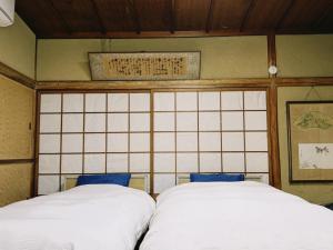 two white beds in a room with a wall at 直島古民家一棟貸し笑くんNaoshima 'Shoukun' Entire house in Naoshima