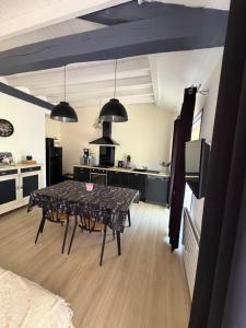 ein Wohnzimmer mit einem Tisch und einer Küche in der Unterkunft Gites Matilon, 5 min Eugénie les bains in Buanes