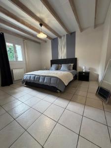 ein Schlafzimmer mit einem Bett und einem großen Fliesenboden in der Unterkunft Gites Matilon, 5 min Eugénie les bains in Buanes + 27 Fotos