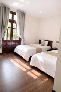a bedroom with two beds and a window at Cherry Villa in Hue