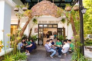 a group of people sitting at tables outside a restaurant at Cherry Villa in Hue