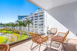 a balcony with chairs and a table with a view of a building at Oceanfront condo with a full kitchen, pool, & beach access in Nuevo Vallarta