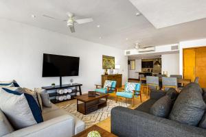 a living room with a couch and a flat screen tv at Stylish condo with covered balcony, pool & pool tables in Nuevo Vallarta