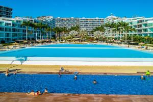 a large swimming pool with people in the water at Oceanfront condo with a full kitchen, pool, & beach access in Nuevo Vallarta