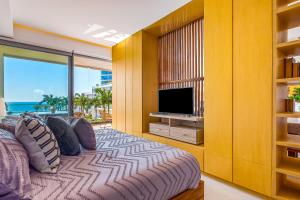 a bedroom with a large bed and a television at Oceanfront condo with a full kitchen, pool, & beach access in Nuevo Vallarta