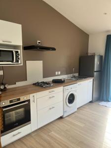a kitchen with white cabinets and a washer and dryer at L'échappée de Bras Long in Entre-Deux