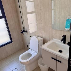 a bathroom with a white toilet and a sink at Ocean Bliss Jacuzzi - Sea View- Check-in in Al Khobar