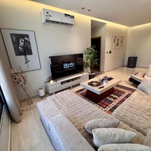 a living room with a couch and a tv at Ocean Bliss Jacuzzi - Sea View- Check-in in Al Khobar