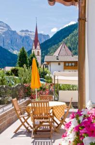 eine Terrasse mit 2 Stühlen, einem Tisch und einem gelben Sonnenschirm in der Unterkunft Residence Villa Gran Baita in Wolkenstein in Gröden