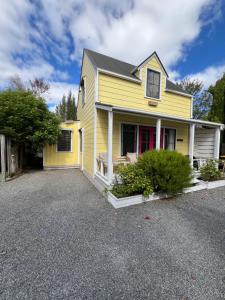 a yellow house with a driveway in front of it at Pinot Villas in Martinborough