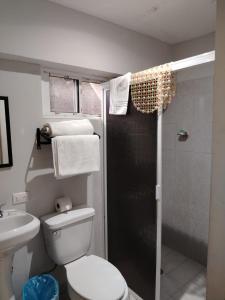 a bathroom with a toilet and a shower with towels at Hgen Rooms & Suites in Los Mochis +44 photos
