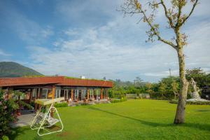 a building with a green yard with a tree at Svargan Lakeside Glamping in Tabanan