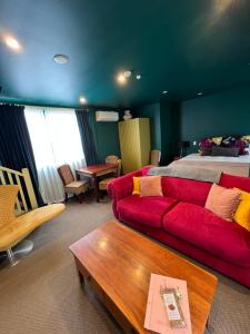 a living room with a red couch and a bed at Pinot Villas in Martinborough