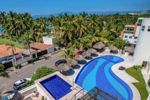 an aerial view of a resort with a swimming pool and palm trees at Ocean-view condo with private rooftop pool, terrace, & resort-style pool in Nuevo Vallarta