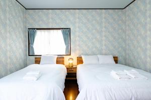 two beds in a room with white sheets and a window at 六鶴亭-ビーチ徒歩8分,スーパー徒歩2分,駅徒歩12分 in Manazuru