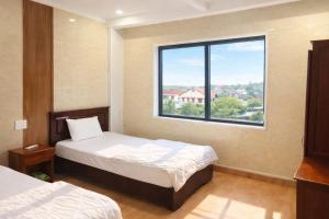 a bedroom with two beds and a large window at Tom Hotel Huế near Phu Bai Airport in Hue