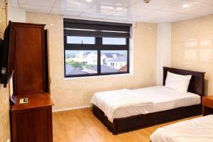 a small room with two beds and a window at Tom Hotel Huế near Phu Bai Airport in Hue