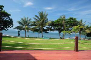 a hammock on a field with palm trees and the ocean at Lomtalay Resort Trat in Ban Bang Pit Lang