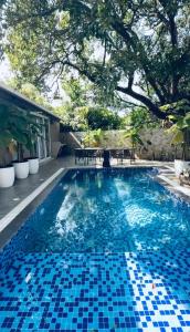 a swimming pool with a blue tile floor and a tree at The S - Luxurious Stays in Mahabaleshwar