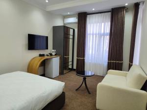 a hotel room with a bed and a couch and a tv at SHOHI ZINDA Hotel in Samarkand