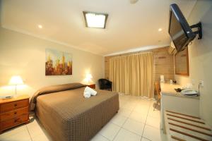 綠寶石鎮的住宿－翡翠中央棕櫚汽車旅館，一间卧室配有一张床、一张书桌和一台电视