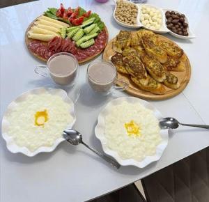 a white table with plates of food and spoons at Karakol Aksuu guest house in Teploklyuchinskoye +10 photos
