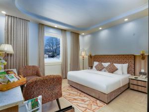 a hotel room with a bed and a chair at Faiz Resort Pahalgam in Pahalgām +28 photos