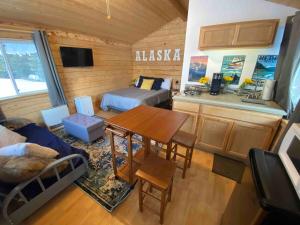 a room with a table and a kitchen with a bed at Rustic Moose Cabin at Moose Tracks Lodging in Kenai